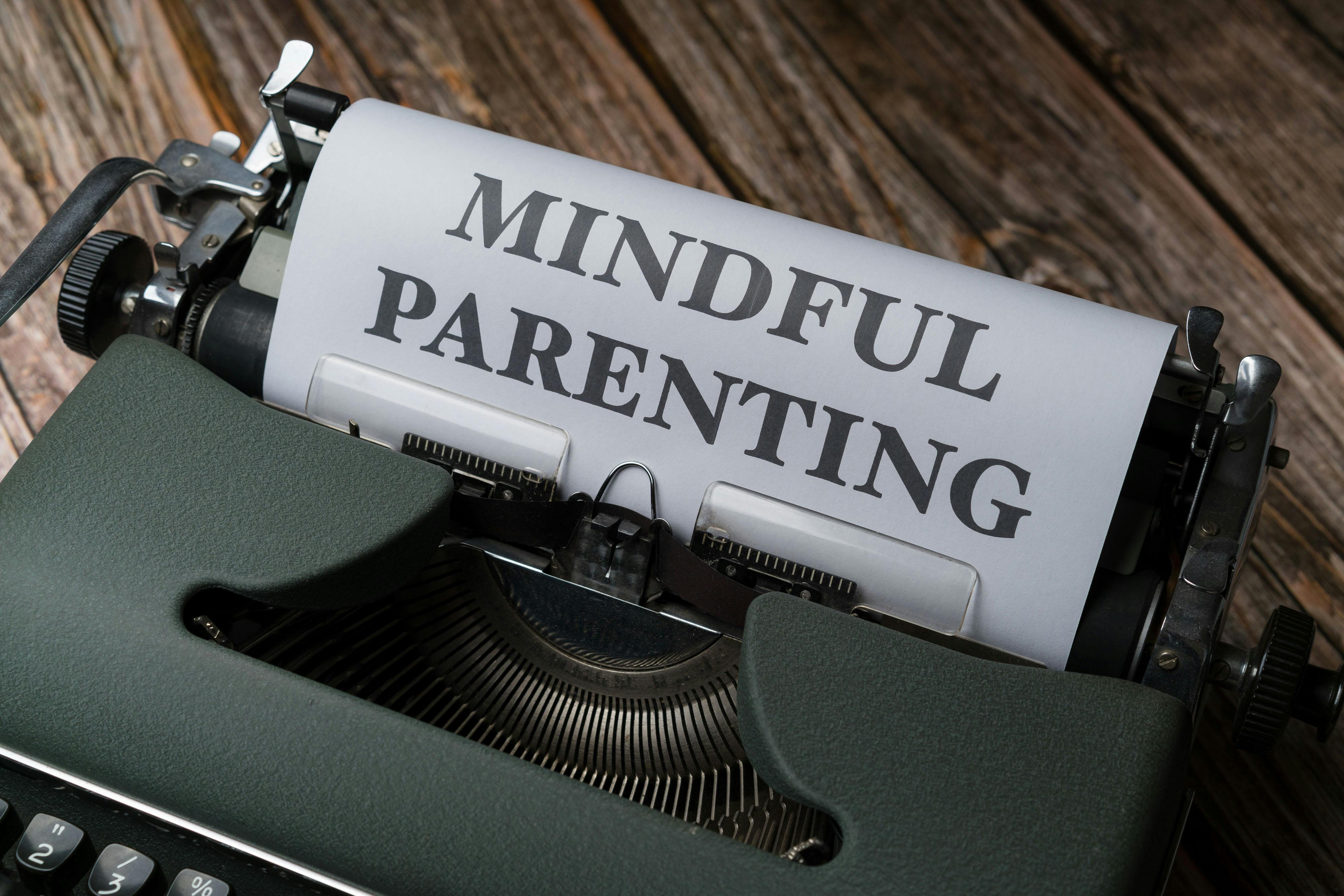 A typewriter with a paper reading 'Mindful Parenting' on a wooden surface.
