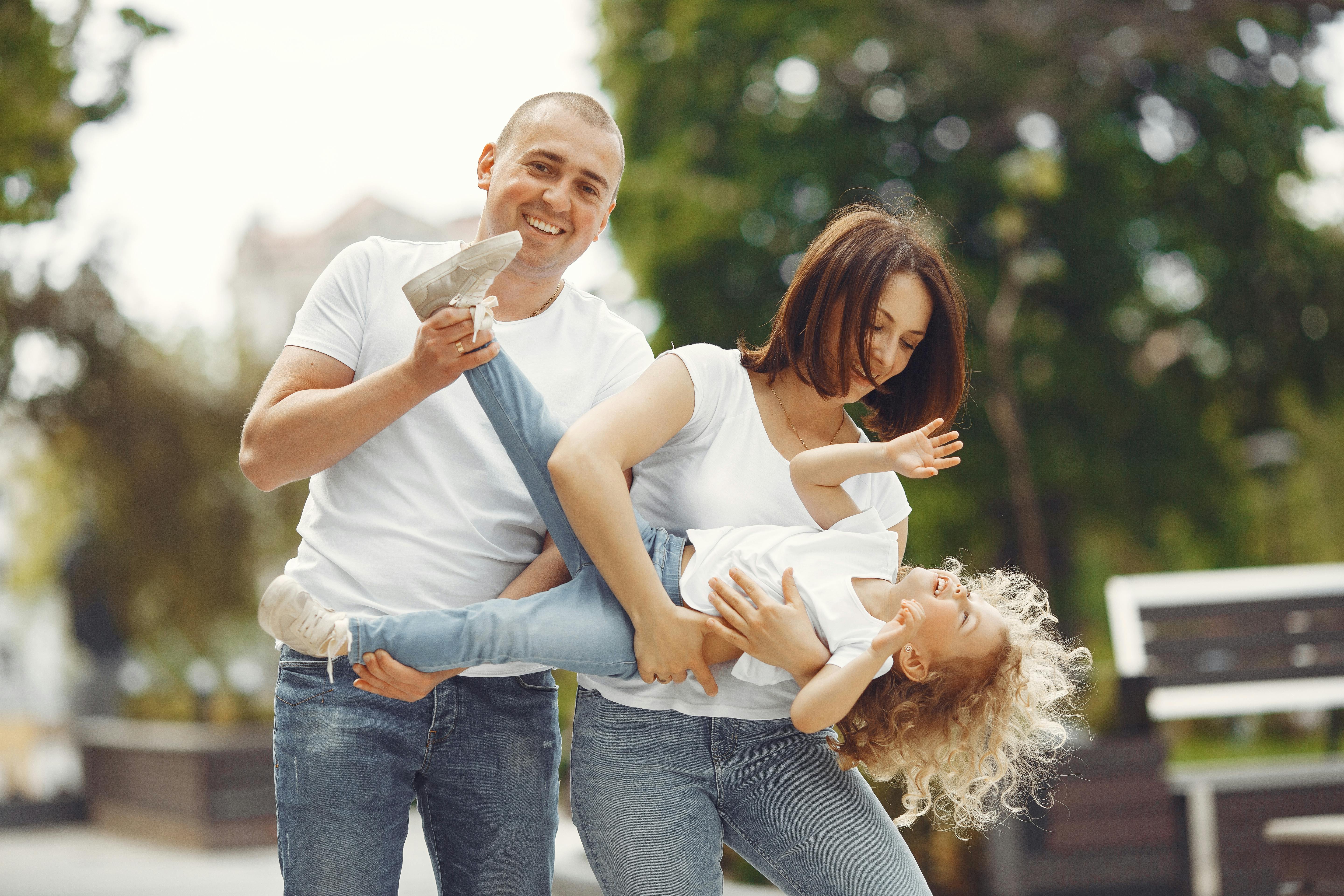 Happy family enjoying playful moments outside on a sunny day.